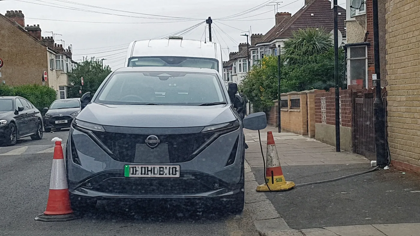 An EV charging cable run loose across a pavement and coned off, photographed in Haringey, north London. This is the practice the Slough scheme is designed to replace; the photo does not show Slough.